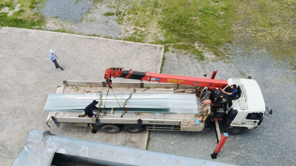 Xe cẩu vận chuyển các tấm lợp lấy sáng composite đến công trình nhà xưởng