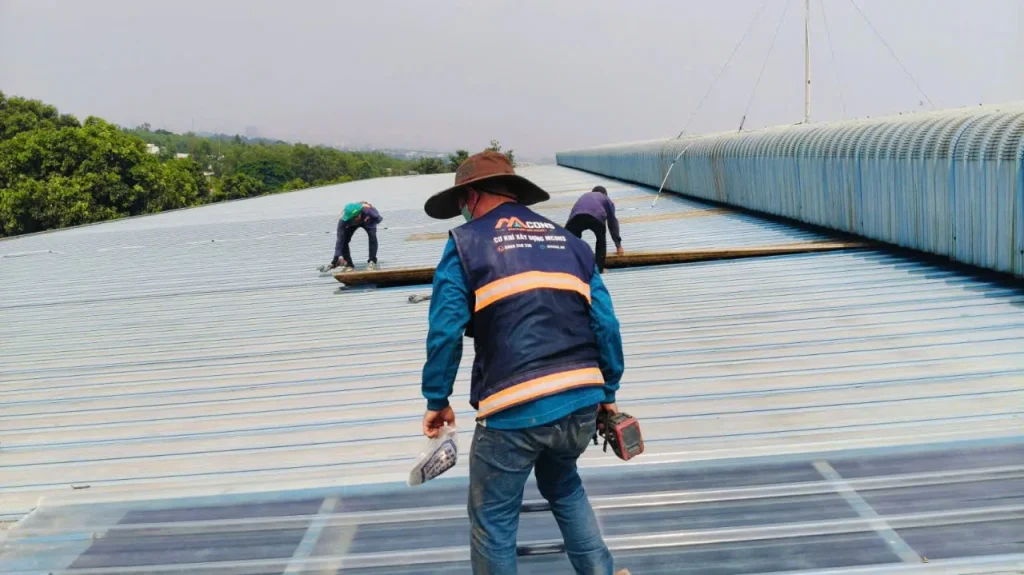 Thợ MCONS bắt vít cố định tấm lấy sáng composite mới trên mái nhà xưởng