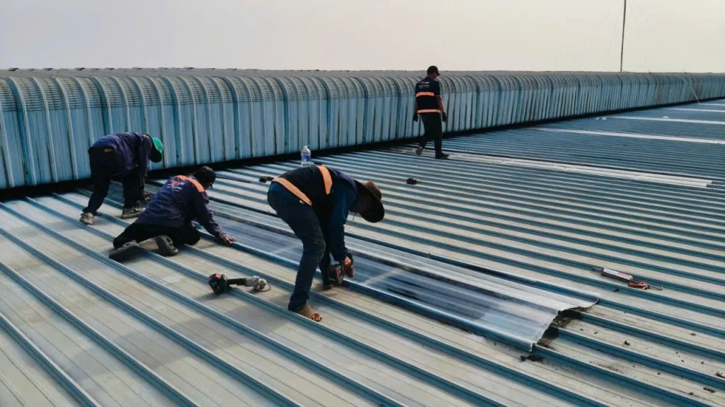Hai thợ MCONS căn chỉnh tấm composite mới tại dải lấy sáng trên mái